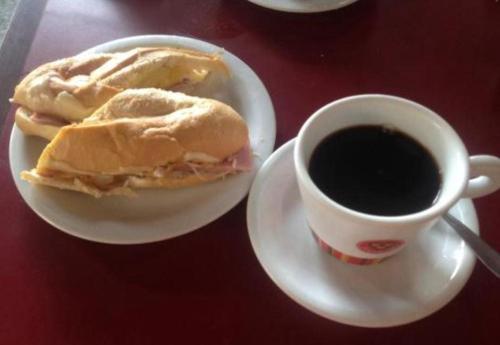 un panino su un piatto accanto a una tazza di caffè di Casa simples e conforto a Belém