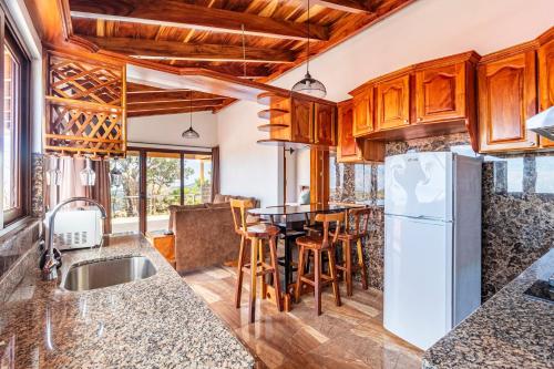 a kitchen with a table and a refrigerator at Casa Ocaso, vistas espectaculares y jacuzzi para relajarte in Tapantí