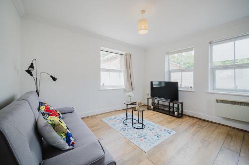a living room with a couch and a television at Central Woking Retreat - Two-bed flat with parking in Horsell