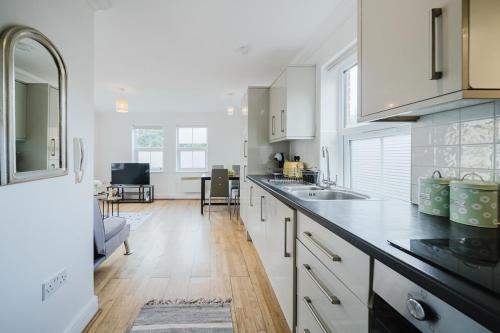 a kitchen with white cabinets and a counter top at Central Woking Retreat - Two-bed flat with parking in Horsell