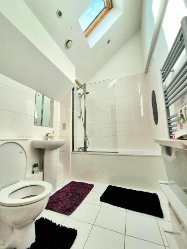 a white bathroom with a toilet and a shower at Explore London: 2 Bedroom House in Wood Green in London