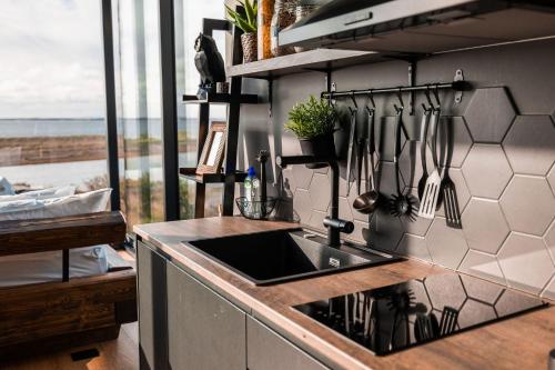 Panorama Glass Lodge WEST في أكرانيس: مطبخ مع حوض وأواني على جدار