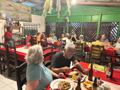 a group of people sitting at tables in a restaurant at Miss Miriam BeachFront Cabins in Tortuguero