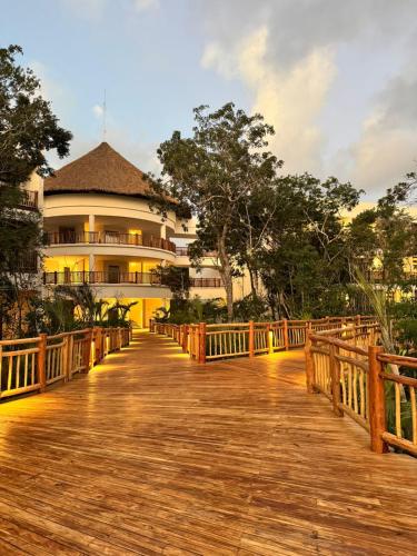 a wooden boardwalk leading to a large building at Hotel Mundo Maya Tulum in Tulum