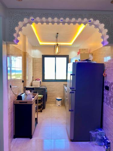 a kitchen with a refrigerator and a living room at Magnifique Appart Tanger Vue Mer Plage à 100m Calme et Nature in Tangier