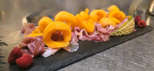 une assiette de nourriture contenant de la viande et des fruits dans l'établissement Relais Villa Olivi, à Costermano