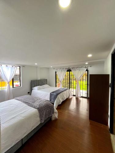 two beds in a room with two windows at Quinta los Parques in Tocancipá