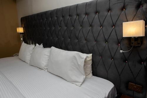a bed with a black padded headboard with white pillows at Mareot Hotel & Spa in Lagos