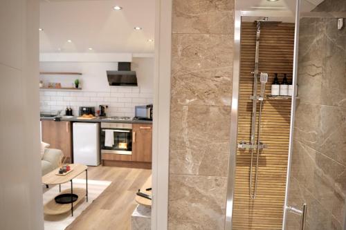 a bathroom with a walk in shower next to a kitchen at Wood & Teal Nest in Bradford