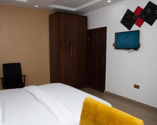 a bedroom with a bed with a yellow chair and a tv at Mareot Hotel & Spa in Lagos