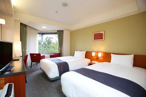 a hotel room with two beds and a flat screen tv at Kyoto Garden Palace in Kyoto