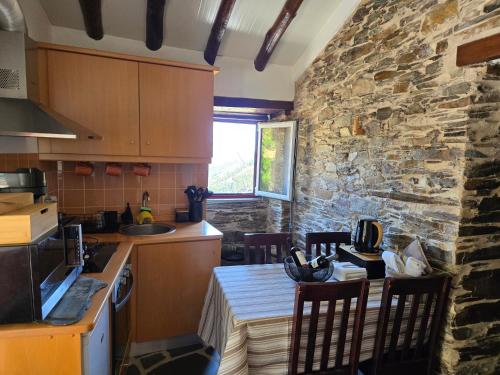 a kitchen with a table and a stone wall at Tojo Natur Piodão in Piódão