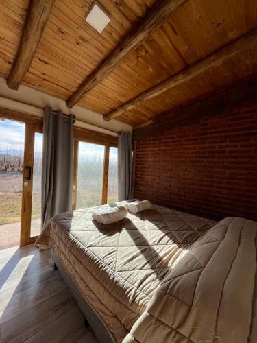 a large bed in a room with a brick wall at Gaucho Mendoza in Malargüe