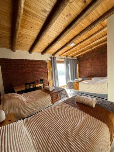 a bedroom with three beds in a room with a brick wall at Gaucho Mendoza in Malargüe