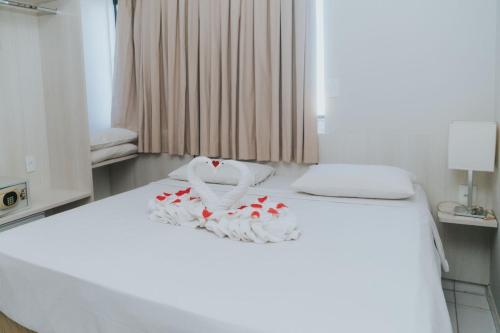 - un lit blanc avec des fleurs rouges dans l'établissement Apto 1203 - Golden Dolphin SUPREME, à Caldas Novas