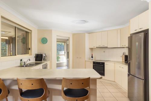 a kitchen with white cabinets and a counter with chairs at Pawprints in Corlette