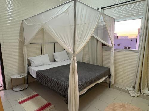 a bedroom with a canopy bed with a window at La Maison des Couleurs in Dakar