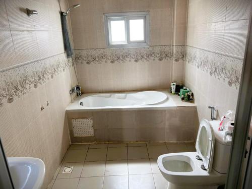 a bathroom with a tub and a toilet and a sink at La Maison des Couleurs in Dakar