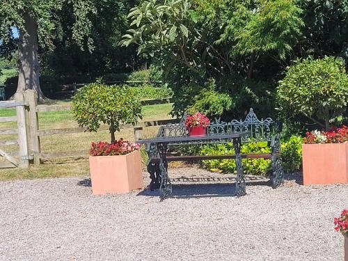 a wrought iron bench with flowers in a garden at Ty Derw Country House B&B in Ruthin