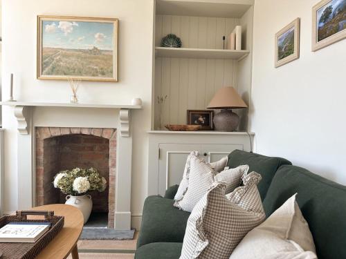 a living room with a green couch and a fireplace at Nursery Cottage in Quorndon