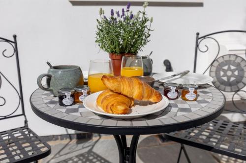 a table with a plate of croissants and orange juice at Nursery Cottage in Quorndon