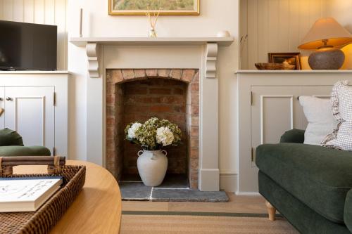 a living room with a fireplace and a green couch at Nursery Cottage in Quorndon