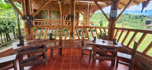a pavilion with wooden tables and chairs on a porch at Hacienda San Miguel Arcangel in Armenia