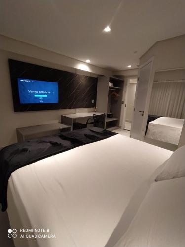 a bedroom with a large bed with a tv on the wall at Flat Beira Mar, Arpoar João Pessoa in João Pessoa