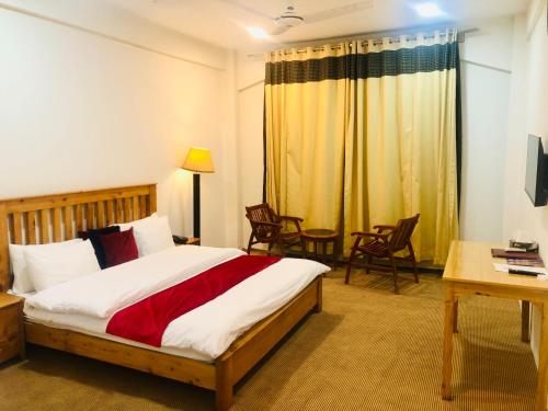 a bedroom with a bed and a desk and chairs at Hispar Hotel Skardu in Skardu