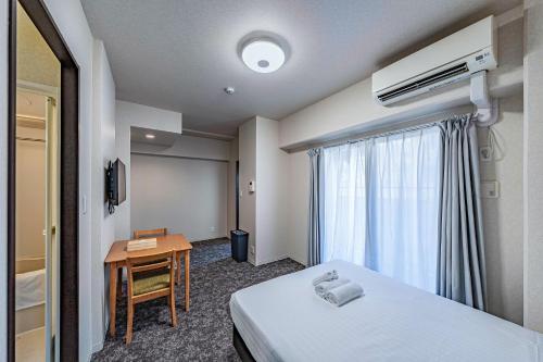 una stanza d'albergo con un letto, una scrivania e una finestra di LABEL 01 Dotonbori Aparthotel ad Osaka