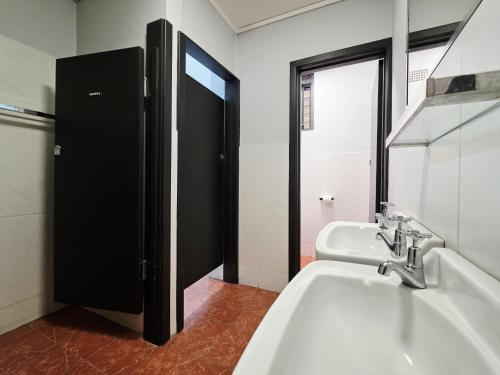 a bathroom with two sinks and a black door at Panania Hotel Sydney in Panania