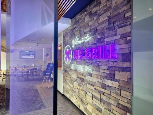 a brick wall with a sign that reads the grille the pit at Panania Hotel Sydney in Panania