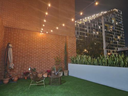 a patio with two chairs and a brick wall with lights at Cómodo loft en centro de zona 4 in Guatemala