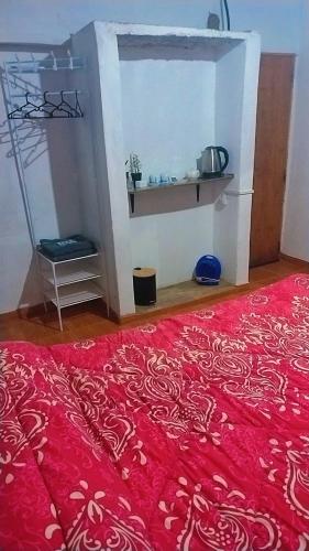 a room with a red bed and a shelf at Hospedaje Familiar Tilcara in Tilcara