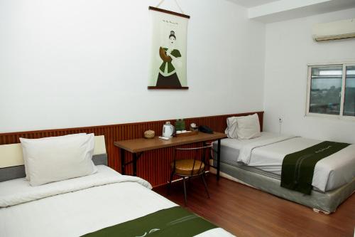 a room with two beds and a table and a desk at Arawa Traveller's Inn Motel in Makassar