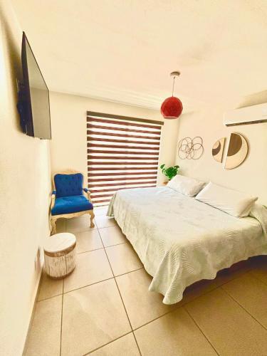 a bedroom with a bed and a blue chair at Departamento Boutique con más Amenidades que Ningún otro en la Zona in Acapulco