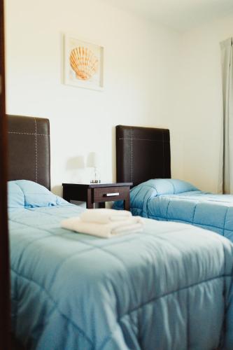 a room with three beds with blue sheets at Casa Pampa Cabañas in Chapadmalal