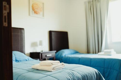 a room with two beds with blue sheets and towels at Casa Pampa Cabañas in Chapadmalal