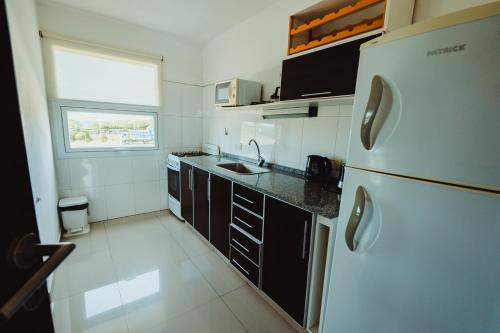 a small kitchen with a refrigerator and a sink at Casa Pampa Cabañas in Chapadmalal