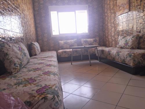 a room with couches and a table and a window at شقة جميلة للكراء اليومي بمرتيل in Martil