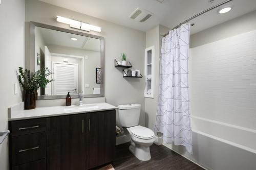 a bathroom with a toilet and a sink and a mirror at Tangerine Terrace -10 min to Disney - Angel Stadium in Orange