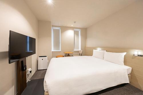 a bedroom with a white bed and a flat screen tv at GRAND HOSTEL LDK Tokyo Nishikasai -GRAND OPENING In May 2025- in Tokyo