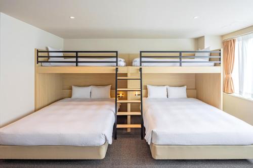 two beds in a room with two bunk beds at GRAND HOSTEL LDK Tokyo Nishikasai -GRAND OPENING In May 2025- in Tokyo