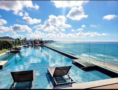 a swimming pool with a view of the ocean at Art Studio - Apartamento em frente ao mar in Salvador