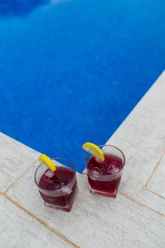 two glasses filled with a drink next to a pool at Caspian Colorful Villas in Lankaran