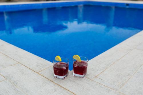 two cocktails sitting on a table next to a swimming pool at Caspian Colorful Villas in Lankaran