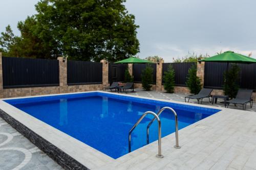 a swimming pool in a backyard with chairs and umbrellas at Caspian Colorful Villas in Lankaran