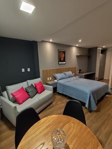 a bedroom with a bed and a couch and a table at Art Stúdio Beira-Mar em Armação 123 in Salvador