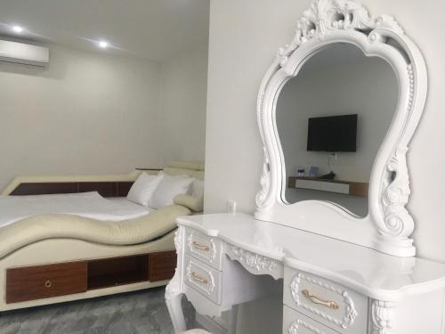 a white bedroom with a bed and a mirror at DONG PHUONG HOTEL in Bao Loc