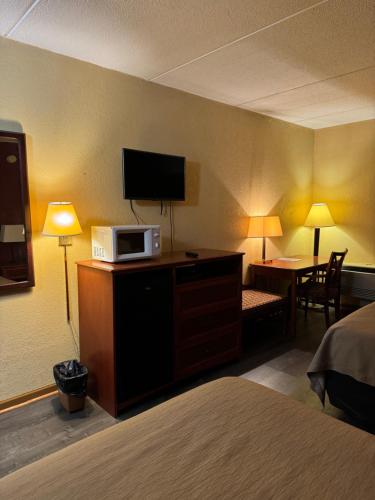 a hotel room with a bed and a microwave on a dresser at Motel Sun Inn in Winthrop Harbor